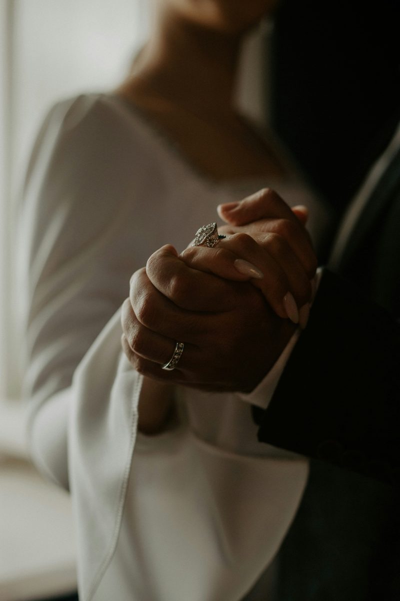Close up of couple holding hands with wedding rings