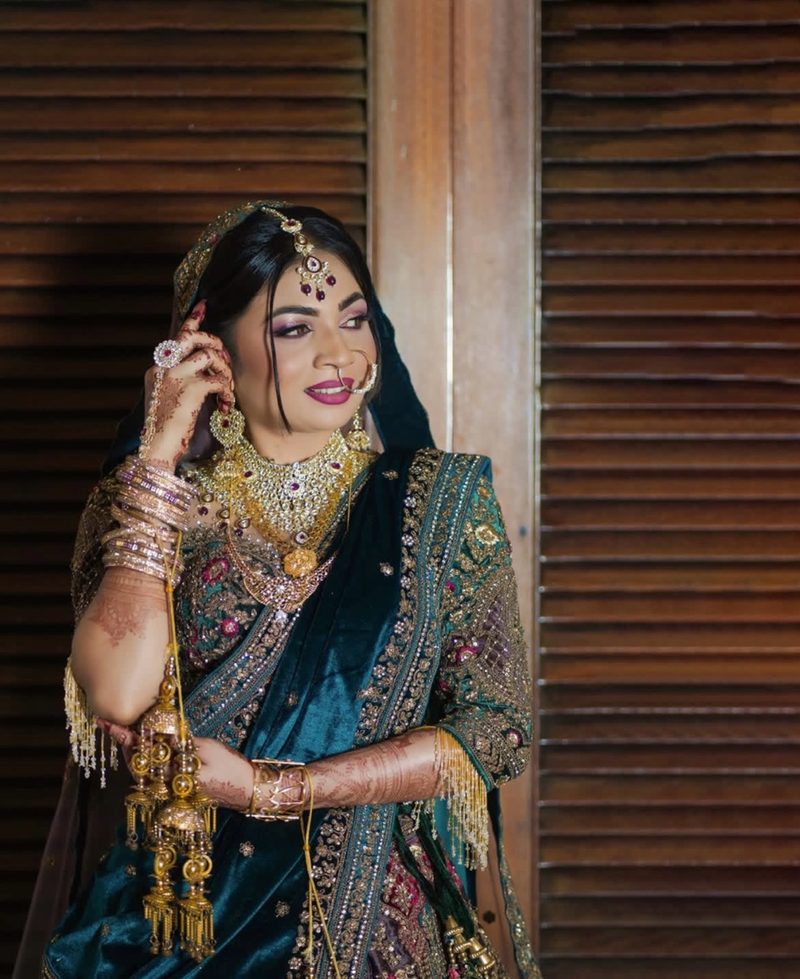Bride in teal lehenga with traditional gold jewelry