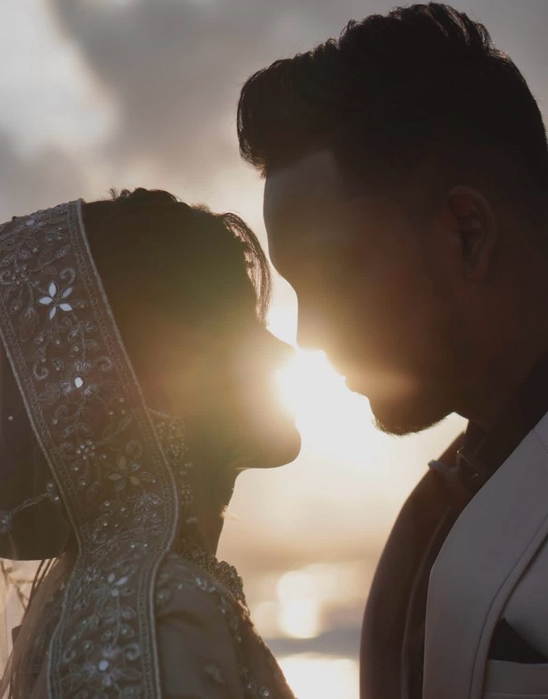 Wedding couple silhouetted against a glowing sunset